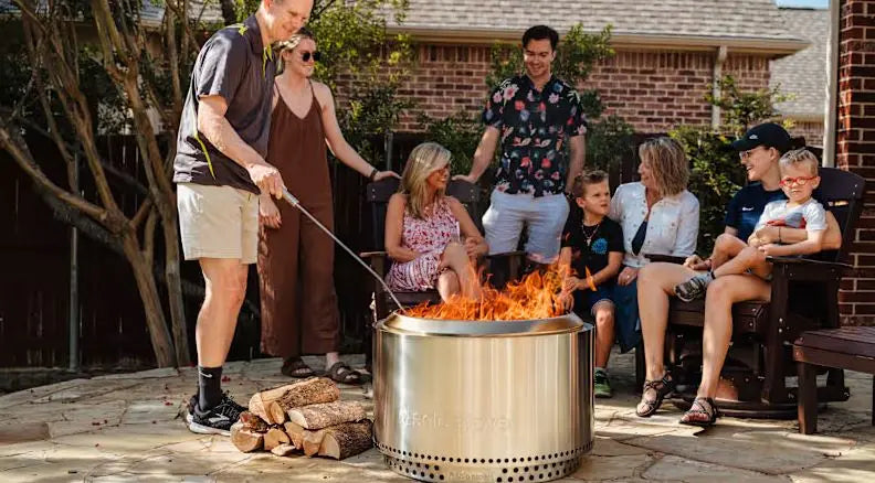 Group gathered around Solo Stove Bonfire with smokeless flames on a modern backyard patio at sunset