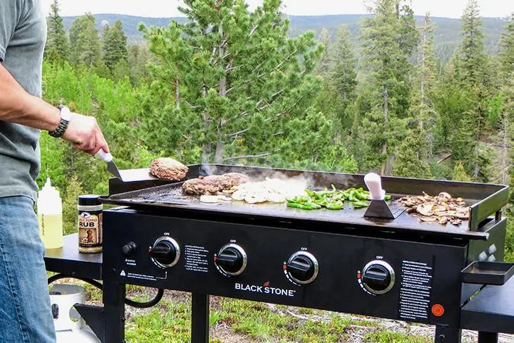Blackstone outdoor kitchen setup with freestanding griddles, pizza oven, and modular pavilion in backyard patio setting