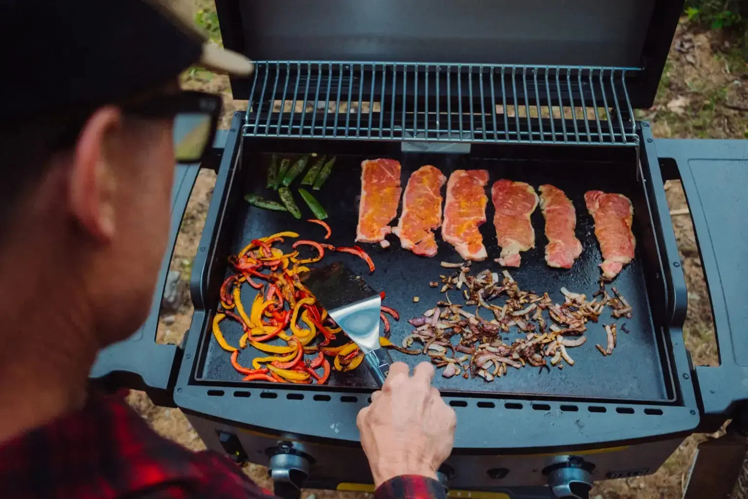 Halo Prime 1100 pellet grill with glowing firebox, patio setting, and wood pellet hopper visible