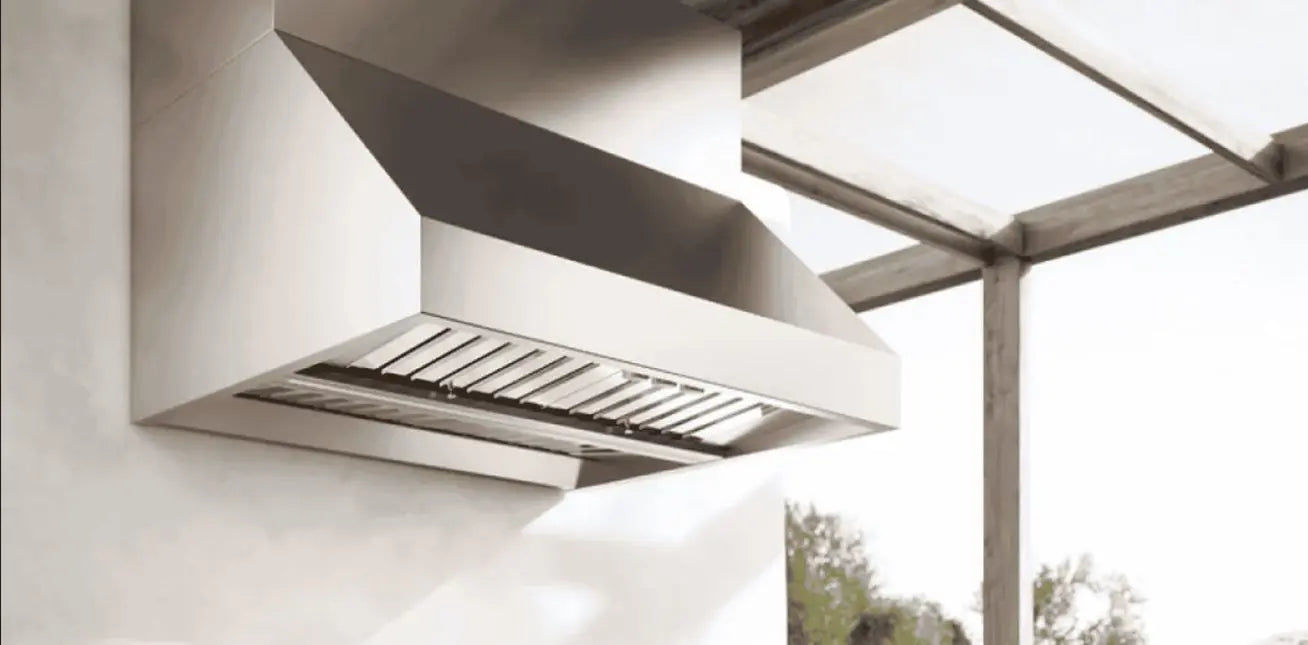 Luxury outdoor kitchen featuring stainless Falmec range hood above a built-in grill island at sunset