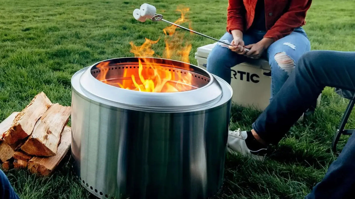 Stainless steel Solo Stove Yukon 2.0 fire pit glowing on a modern patio deck at sunset