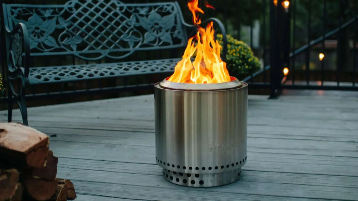 Solo Stove Ranger 2.0 smokeless fire pit lit at night on a deck with flames glowing